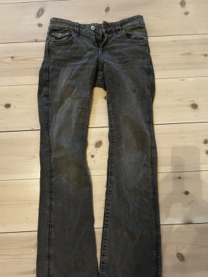 Mörkgrå bootcut jeans - Snygga mörkgrå jeans med bootcut passform och klassiska fem fickor. Jeansen har knappgylf och detaljerade bakfickor med lock och knapp. Perfekta för en avslappnad men trendig look. Perfekta för mig som är 164 cm.