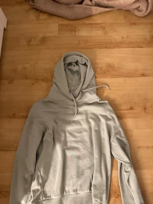 Ljusgrön hoodie med huva - En stilren ljusgrön hoodie med klassisk huva och dragsko. Hoodien har en avslappnad passform och är tillverkad i mjukt material, perfekt för en chill och bekväm look. Inga synliga loggor eller tryck på framsidan.
