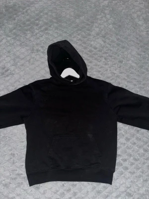 Svart hoodie från Zara - En klassisk svart hoodie från Zara med stor känguruficka framtill och huva. Hoodien har en enkel och clean design utan tryck eller mönster, 