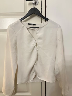 Vit omlottblus från BikBok - Stilren vit omlottblus från BikBok med lång ärm och unik twistad detalj framtill. Bra skick! 
