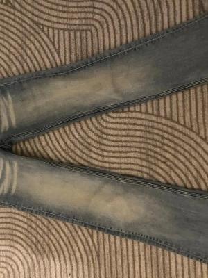 Ljusblå jeans - Säljer mina helt nya ljusblå jeans från Cheap Monday med slitningar och en grön patch med logga på bakfickan. Jeansen har klassisk femficksmodell och är tillverkade i bomull med en tight passform. Perfekta för dig som gillar streetstyle.