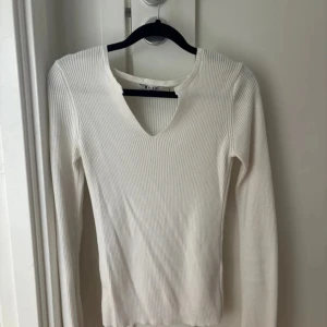 Vit ribbad långärmad tröja NA-KD - Säljer en vit ribbad långärmad tröja från NA-KD i storlek XS. Tröjan har en v-ringning med liten cutout vid halsen och är i stretchigt material som sitter skönt på kroppen. 