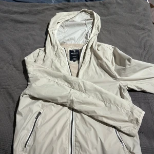  Vindjacka Boggi Milano - Snygg beige vindjacka från Boggi Milano med huva och dragkedja framtill. Jackan har två fickor med dragkedja och meshfoder på insidan för extra komfort. Jackan är i storlek S men passar Xs eller dig runt 167-173. Skriv för fler funderingar!