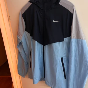 Nike Vindjacka - Blå, köptes för 3 månader sedan knappt använd. Storlek M är i helt nytt skick inga fläckar eller någonting. Säljs då den inte passar mig.