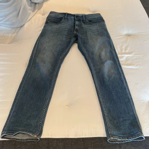 Blå jeans Tiger of Sweden IGGY 32/32 - Snygga blå jeans från Tiger of Sweden, modell IGGY. Klassisk femficksdesign med raka ben och normal passform. Jeansen har en cool tvättad look och är tillverkade i slitstarkt denim. Perfekta för dig som gillar stilrena och tidlösa jeans.