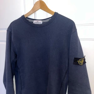 Stone Island tröja - Snygg marinblå sweatshirt från Stone Island i fint skick. Storlek L men passar mig som brukar ha M. Säljer då jag inte använder den längre.