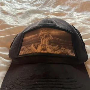 Svart keps från Berretto med fototryck - Svart keps från Berretto med mesh på sidorna och ett coolt fototryck framtill som visar ett sportigt firande. Kepsen har klassisk böjd skärm och justerbar passform. Perfekt för dig som gillar sport och vill sticka ut med en unik detalj.