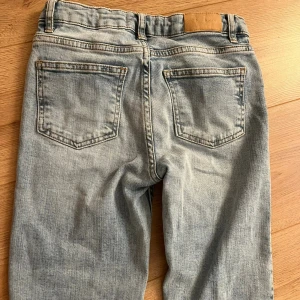 Ljusblå low waist bootcut jeans från Gina Tricot - Snygga ljusblå jeans från Gina Tricot med klassisk femficksdesign och bootcut-ben. Jeansen är low waist, slitna detaljer vid benslut och är tillverkade i bomullstyg med en skön jeanskänsla. Perfekta för en avslappnad och trendig look.