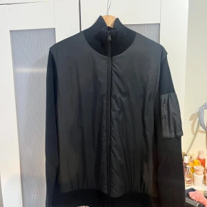 J.Lindeberg hybrid jacka / cardigan / höstjacka/ knitted cardigan - Jätte fin J.Lindeberg Beck knitted hybrid jacket/ jacka Perfekt inför hösten som höstjacka Storlek L på lappen Jackan är i jätte bra och fint skick Svart färg med svart logga på vänster sida arm Skicka meddelande vid några funderingar  Kolla gärna även in mina andra annonser