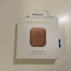 Ny Ideal of Sweden Camel Croco AirPods Case - Elegant AirPods-fodral i Camel Croco-design från Ideal of Sweden. Passar AirPods 1:a och 2:a generationen. Snyggt mönster, skyddar mot repor och stötar. Produkten är helt ny och levereras i originalförpackning.