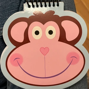 Anteckningsblock apa - En söt spiralbunden anteckningsbok formad som ett apa-ansikte. Perfekt för att skriva ner tankar, idéer eller skisser. Den lekfulla designen gör den till en rolig accessoar i väskan och passar både unga och unga vuxna som gillar djur och kreativitet.