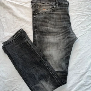 Svarta jeans med grå tvätt från BOSS - Snygga svarta jeans från BOSS med grå tvätt. Dom har defekter på sig.jag har  lagt en klister lapp i jeansen så dem inte ska gå sönder dem har slitis upp vid greven. Kom med frågor och funderingar.🤙👍