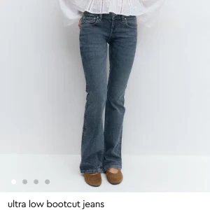 Blå ultra low bootcut jeans - Snygga blå jeans med ultra låg midja och bootcut-ben. Jeansen har coola broderade detaljer på bakfickorna och klassisk femficksdesign. Perfekt för dig som gillar en avslappnad men trendig look. Har använt den 1 gång o sen insåg jag att de va för små :( 