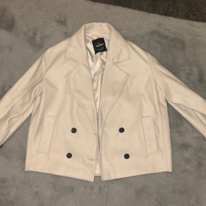 Beige jacka från Pull&Bear - Stilren beige skepparkavaj från Pull&Bear med dubbelknäppning och stora svarta knappar. Sitter som XL, endast använd en gång men inga tecken på det.