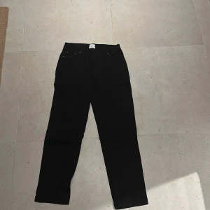 Svarta jeans från Grunt organic - Svarta jeans från Grunt i ekologisk bomull. Klassisk femficksmodell med raka ben och normal passform. Snygg minimalistisk look med svart patch bak i midjan och diskreta sömmar. Perfekta för dig som gillar stilrena och enkla jeans.