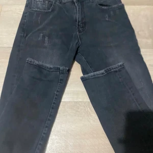 Svarta jeans från Dolce & Gabbana - Snygga svarta jeans från Dolce & Gabbana med DG-logga på bakfickan och diskreta slitningar för en cool look. Klassisk femficksmodell med raka ben och bra  passform, Storlek W32 L32. Dessa jeans finn ej längre 
