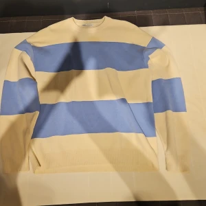 Randig tröja från Zara i blått och beige - Säljer en snygg randig tröja från Zara i storlek M. Tröjan har breda blå och beige ränder, rund halsringning och långa ärmar. Perfekt för dig som gillar en stilren men ändå lekfull look. Perfekt för dig som vill vara fint klädd och varm på samma gång.