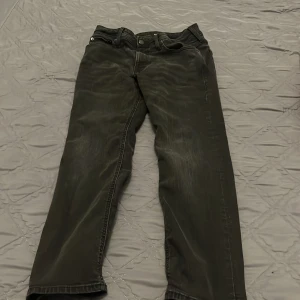 Svarta jeansbyxor med raka ben - Säljer ett par svarta jeansbyxor med klassisk femficksdesign och raka ben. Jeansen har diskreta slitningar och en mörk tvätt som ger en cool look. Materialet är jeans och passformen är normal. Perfekta för dig som gillar en enkel men snygg stil. Orginal pris är 500