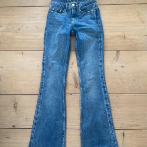 Blå bootcut jeans från Gina Tricot - Snygga blå jeans från Gina Tricot, modell Perfect Jeans. Klassisk femficksdesign, bootcut-ben och normalhög midja. Jeansen är i ett mjukt denimtyg med lätt tvättad look och har detaljerade sömmar och knappstängning framtill.