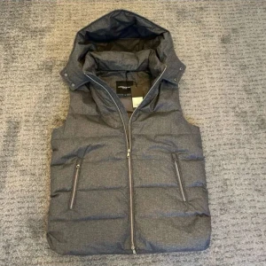 Grå dunväst från Lawrence Grey - Snygg grå dunväst från Lawrence Grey med huva och två dragkedjefickor framtill. Västen är helt ny med alla tags. Perfekt för lager-på-lager och har en stilren look med diskret melerad yta.
