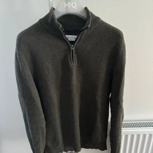 Mörkgrön stickad half zip från These Glory Days - Säljer en mörkgrön stickad tröja från These Glory Days i storlek medium. Tröjan har en snygg half zip-dragkedja vid kragen och är långärmad med en diskret, ribbad struktur. Perfekt för lager-på-lager under hösten och vintern.