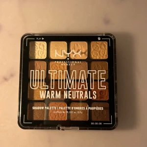 NYX Ultimate Warm Neutrals ögonskuggspalett - NYX Ultimate Shadow Palette Warm Neutrals med 16 nyanser i varma toner som beige, guld, brons, koppar och brunt. Paletten har både matta och skimrande skuggor i fyrkantiga pans med mönster. Paletten är enbart testad ett fåtal gånger och i gått skick! 