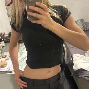 Svart croppad t-shirt topp Brandy Melville - En svart croppad topp med korta ärmar och rund halsringning. T-shirten är i mjuk bomull och har en enkel, stilren design som passar till det mesta. Perfekt för dig som gillar en basic men trendig look.