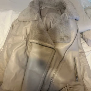 Beige teddyjacka med dragkedja XXL - Säljer en snygg beige teddyjacka i storlek XXL med mjukt foder och stor krage. Jackan har silvriga dragkedjor och detaljer, samt en schysst oversized look. Perfekt för dig som vill ha en varm och trendig jacka med coola vibbar.