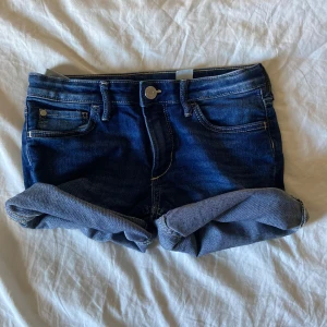 Mörkblå jeansshorts med uppvik - Snygga mörkblå jeansshorts från Denim med klassisk femficksdesign och uppvikta benslut. Shortsen har synliga kontrastsömmar, knapp och dragkedja framtill samt bälteshällor. Perfekta för varma dagar och enkel att matcha med allt. Säljer eftersom den blivit för liten💗💗