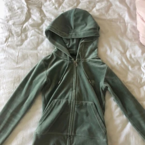 Grön zip hoodie med huva - Mysig grön hoodie med dragkedja framtill och stor huva. Tröjan har långa ärmar, fickor på sidorna och justerbara soppar i huvan. Perfekt för en avslappnad stil och enkel att matcha med jeans eller leggings.