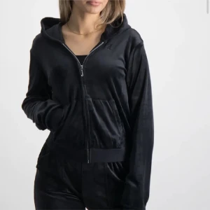 Svart velour hoodiejacka med dragkedja - Mjuk och skön svart hoodiejacka i velour med dragkedja framtill och huva. Jackan har långa ärmar, ribbade muddar och en stor ficka framtill. Perfekt för en chill och avslappnad look. Barnstorlek men sitter som en vanlig xs. Skriv priv för flera bilder