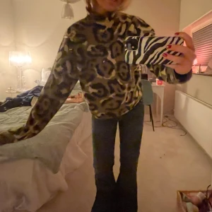 Leopardmönstrad stickad  - Säljer en supermjuk stickad polotröja med leopardmönster i bruna, svarta och beige toner. Tröjan har hög krage och långa ärmar, perfekt för att hålla sig varm och ändå sticka ut. Oversized fit för en chill vibe.