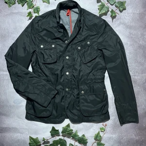 J.Lindeberg Technical Field Jacket – Storlek M - Stilren och funktionell jacka från J.Lindeberg, känd för sin skandinaviska design och höga kvalitet.  🎨 Färg: Svart 📏 Storlek: Medium (M) 📐 Mått: Fråga ifall det önskas! ♻️ Skick: Mycket bra – lätt använd, inga fläckar eller defekter 🧵 Material: Nylon / Polyesterblandning  ‼️ Skickas dagen efter köpet genomförs! ‼️