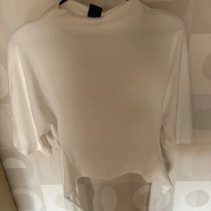 Vit tie back T-shirt från Gina Tricot - Säljer denna tröjan som är helt ny, aldrig använd! Prislappen sitter kvar och nypris är 300kr