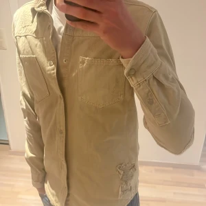 Beige overshirt sliten - En asfet skjorta/overshirt i jeans material. Passar perfekt nu under hösten! Jättesvår overshirt att få tag på nästan omöjligt. Pris kan diskuteras!