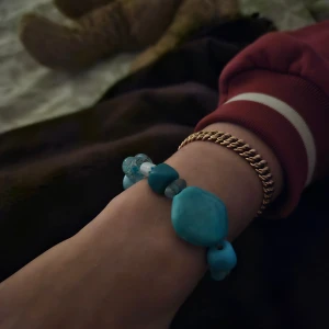 Blått pärlarmband med olika former - Unikt armband med pärlor i olika blå nyanser och former, från ljusblått till djupblått. Några pärlor är transparenta och andra har marmorerade mönster. 