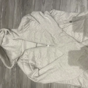 Vit quiltad pufferjacka från H&M - Snygg vit pufferjacka från H&M med quiltade partier och huva. Jackan har dragkedja framtill och sidofickor med knapp. Perfekt för kyliga dagar och enkel att matcha med olika outfits.