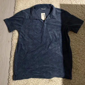 Blå frotté pikétröja från Kappahl - Mjuk och skön blå pikétröja från Kappahl i frotté. Klassisk krage och korta ärmar. Helt ny aldrig använd då pris lappen sitter kvar storlek är 170. Bara höra av sig vid funderingar.🤗