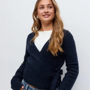 Mörkblå omlottkofta med knyt - Säljer en mörkblå omlottkofta med knyt i sidan och v-ringad hals. Koftan är stickad och har långa ärmar samt ribbade muddar. Perfekt för lager-på-lager och ger en chill men ändå snygg vibe.🥰