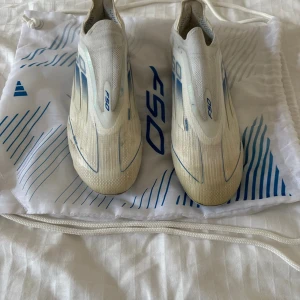 Adidas F50 Elite fotbollsskor vita/blå - Säljer ett par av Adidas F50 Elite FG super snygga fotbollskor som är vita med isblå sträck recomenderar starkt kommer med orginalpåse skriv vid mista lilla fundering skorna görs rent innan de säljs
