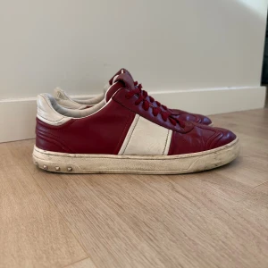 Valentino Rockrunner sneakers röd/vit - Tja, jag säljer ett par valentino rockrunners, de är vinröda i hyfsat bra skick, 5 nitar är borta. Skorna är lite skitiga men går absolut att tvätta bort. Skorna är i storlek 40 men passar 41.                                                      Jag har tänkt mig runt 2000kr men priset är inte hugget i sten!
