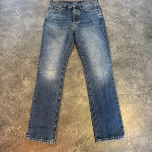 Blå jeans med snygg slitning - Ett par jeans från Taktil  med snygg slitning fram och bak. Knappt använda och i mycket gott skick. Storlek 29/32 men passar mer som 30/32.