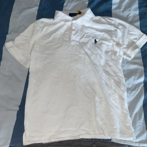 pikétröja Polo Ralph Lauren - Klassisk vit pikétröja från Polo Ralph Lauren i modellen Custom Slim Fit. Loggan i marinblått på bröstet. Tillverkad i mjuk bomull som är skön mot huden.