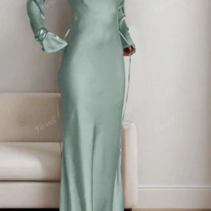 Ljusgrön långklänning i satin - Supersnygg ljusgrön långklänning i glansig satin med långa trumpetärmar och snörning i midjan för en extra snygg siluett. Klänningen har en elegant och stilren look som verkligen sticker ut.