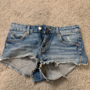 Blå jeansshorts från H&M Divided - Säljer ett par blå jeansshorts från H&M Divided i storlek 34. Ganska små i storleken