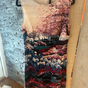 Blommig ärmlös klänning Concept Club XL - Supersnygg ärmlös klänning från Concept Club med färgstarkt blommönster och naturmotiv i rosa, blått, vitt och rött. Klänningen har rund halsringning och dragkedja bak. Perfekt för dig som vill sticka ut med en unik look!