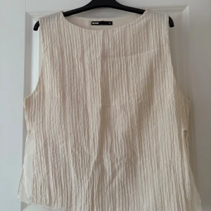 Beige linnetopp från Bik Bok - Säljer en beige linnetopp från Bik Bok i storlek XL. Toppen är ärmlös och har en snygg, krinklad struktur som ger en cool och avslappnad vibe. Perfekt för varma dagar och enkel att matcha med jeans eller shorts.