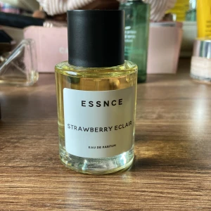 Essnce Strawberry Eclair Parfym - Trendig Eau de Parfum från Essnce med namnet Strawberry Eclair. Perfekt för dig som vill sticka ut med en unik doft. Enkel och stilren flaska som passar in i alla badrumshyllor. Sprayad en gång, köpt för en veckan sen så helt ny. 