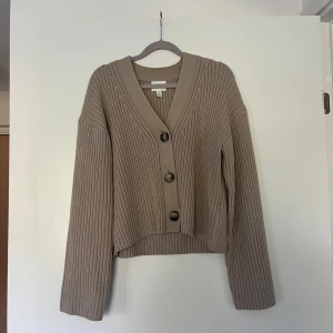 Stickad tröja  - Beige stickad tröja med knappar från HM. Xs men stor i storleken. Endast använd fåtal gånger. Inga anmärkningar. Perfekt till hösten!!