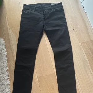 Svarta skinny jeans från Diesel - Svarta jeans från Diesel med klassisk femficksdesign och tydlig logotyp på bakfickan. Modellen är skinny fit med smala ben och låg midja. Jeansen är tillverkade i ett stretchigt bomullsmaterial som ger en bekväm passform och snygg siluett.